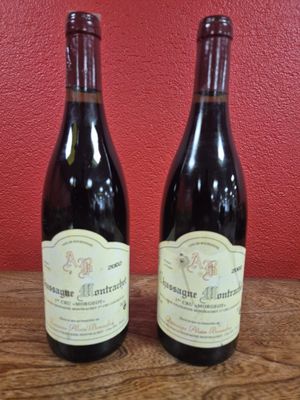 Deux bouteilles de vin sont posées sur une table devant un mur rouge.