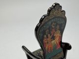 a miniature chair with a painting on the back of it