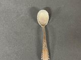 a silver spoon with a shell on it on a table