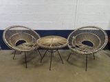trois chaises en osier et une table dans une pièce