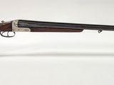 un fusil avec un canon en bois, posé sur un socle en acrylique transparent