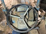 a steering wheel of a tractor that is sitting in the dirt