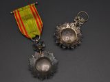 two medals and a ribbon on a black surface