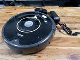 un aspirateur robot posé sur une table en bois, avec son chargeur