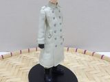 anime figurine of a man in a white coat standing on a wooden floor