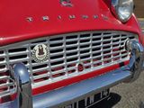 un gros plan d'une voiture rouge avec un insigne à l'avant