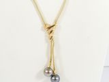 a gold necklace with two black pearls hanging from it