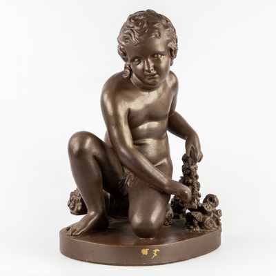 une statue antique en bronze représentant un garçon avec des raisins