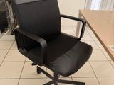 a black office chair sitting in front of a computer desk