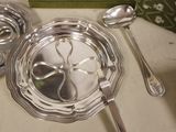 a silver plate with a spoon and a spoon rest on a table
