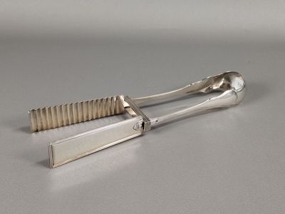 pair of silver plated tonges with handles on a gray surface