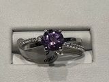 une photo d'une bague en diamant violette dans un écrin blanc