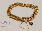 un bracelet en chaîne d'or orné d'une breloque en forme de perle rouge