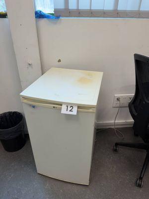 a small white refrigerator next to a black chair in a room