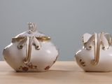 two white and gold teapots sitting on a wooden table