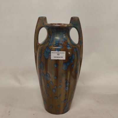 a blue and brown vase sitting on a white surface