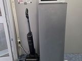 a silver refrigerator and a black vacuum on the floor