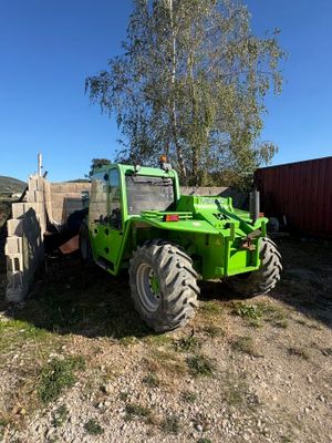 a green tractor that is parked in the dirt