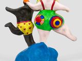 statue of a woman and a dog on a rock with a ball