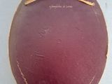 a purple oval box with a gold handle on a white surface