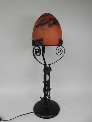 lampe de table en fer forgé avec un abat-jour couleur coquille d'œuf, posée sur un pied