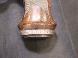 a close up of a silver and wood object on a table