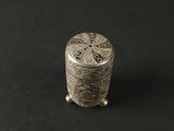 une vieille salière en argent posée sur une surface noire