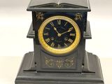 une horloge noire et dorée sur laquelle est posé un livre