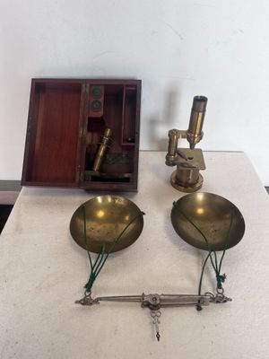 deux balances en laiton posées sur une table, à côté d'une boîte en bois