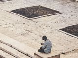 a man sitting on a bench and looking at his cell phone