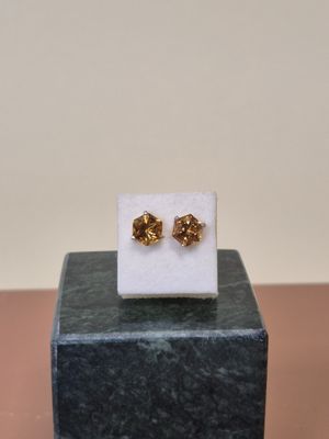 Les petites boucles d'oreilles en forme de nœud dorées sont posées sur un bloc de marbre