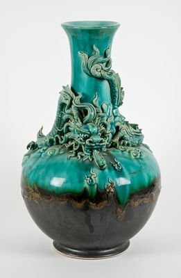 un vase vert orné d'un dragon, posé sur une table