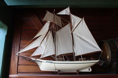 une maquette de voilier posée sur une étagère à côté d'un tonneau