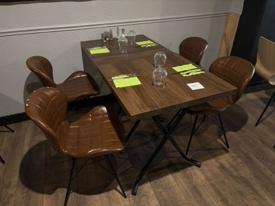 une table en bois avec quatre chaises et un verre de vin posé dessus