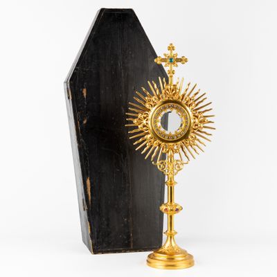 un coffret doré et noir surmonté d'une croix