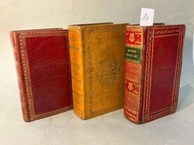 three old books are lined up in a row on a white surface