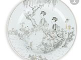 une assiette blanche sur laquelle est représentée une femme et un oiseau