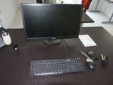 un écran d'ordinateur, un clavier et un téléphone posés sur un bureau