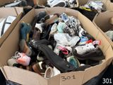 de nombreuses paires de chaussures dans une boîte en carton posée par terre