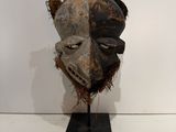 an image of a wooden mask on a stand on a white surface