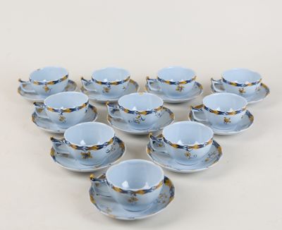 six tasses et soucoupes sont disposées en forme de cœur sur une surface blanche