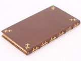 brown book with gold crosses on it on a white surface