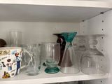 many glasses and vases on a shelf in the kitchen