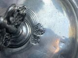 a close up of a silver plate with a bird on it
