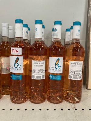 six bottles of rose wine are lined up on a shelf