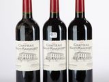 trois bouteilles de vin rouge posées l'une à côté de l'autre sur une surface blanche