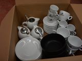 une boîte remplie d'assiettes, de tasses et de cuillères blanches
