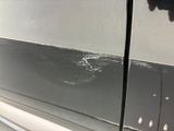 the side of a car with a cracked door and a dent in it