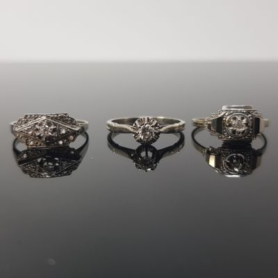 three silver rings with diamonds on a black surface