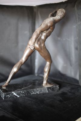 une statue en bronze représentant un homme tenant une raquette de tennis